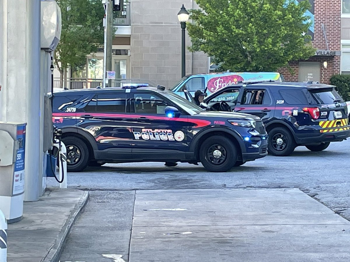 Police activity at Buckhead gas station.  1 person w injured foot. 2 other sitting in back of squad car.